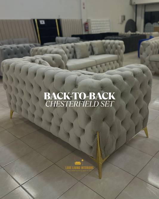 Gray tufted sofa set with gold legs on a tiled floor, labeled 'Back-to-Back Chesterfield Set'.