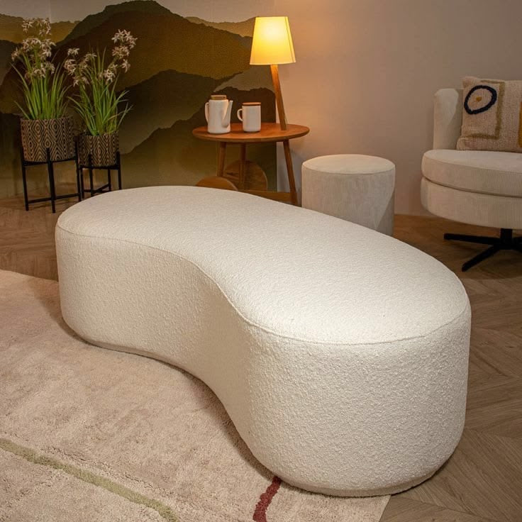 Cream bouclé Pebble curved kidney-shaped ottoman bench in a modern lounge