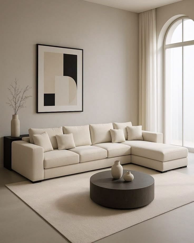 Cream fabric Hampton L-shape couch with chaise, square arms and dark plinth base in a minimalist lounge