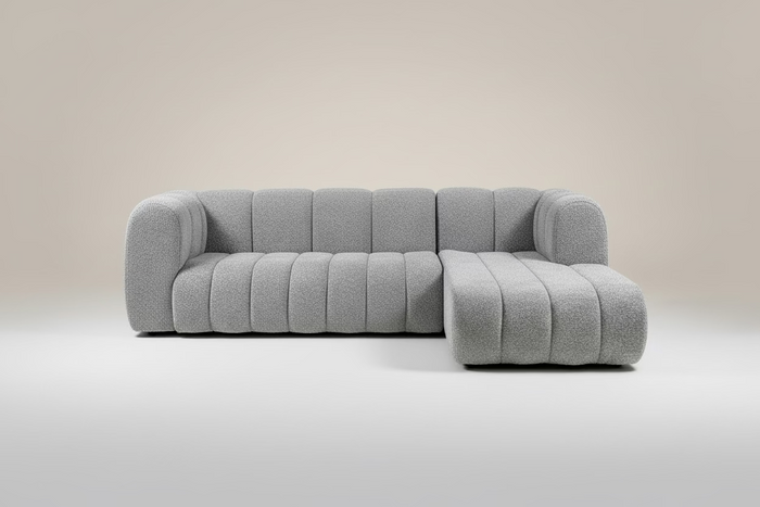 Gray textured sectional sofa in a showroom setting with tables and other furniture.