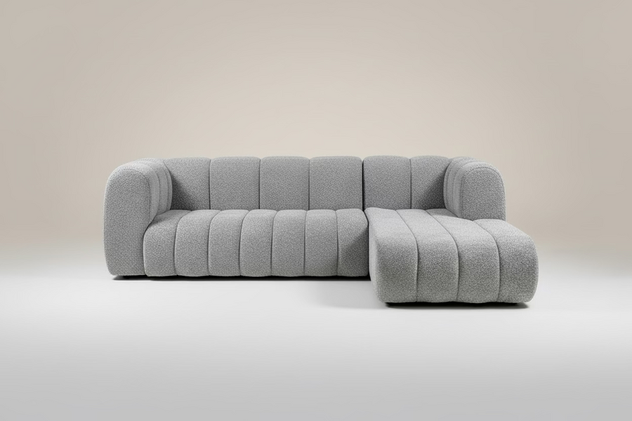 Gray textured sectional sofa in a showroom setting with tables and other furniture.